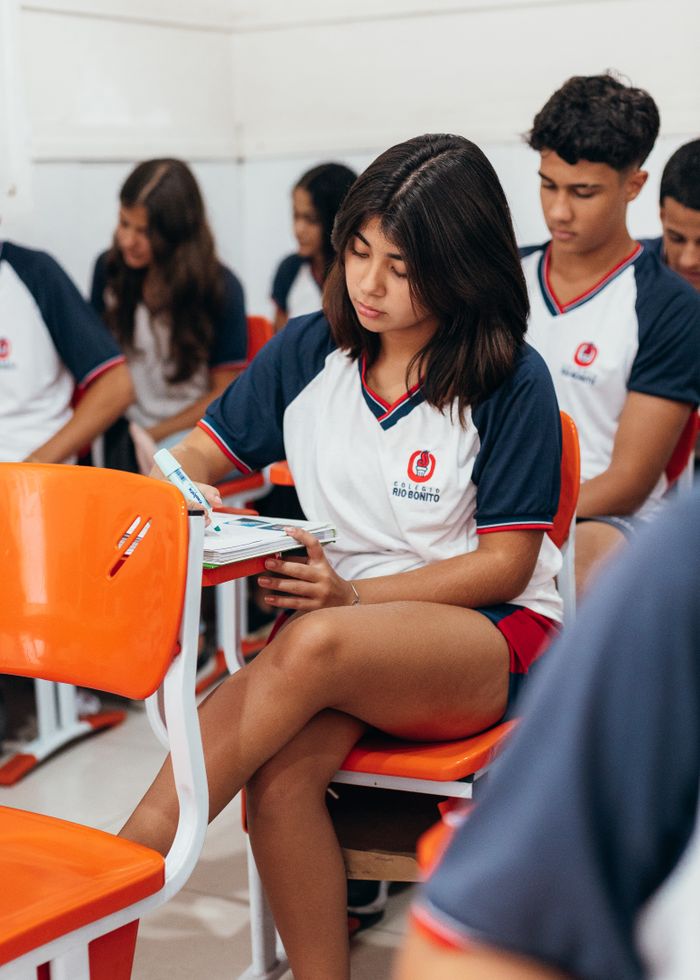 services-01 Group of students in school uniforms taking an exam in a classroom setting.