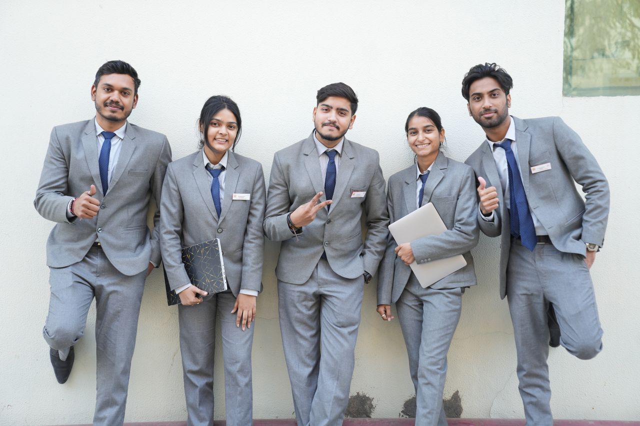 services-02 Group of young professionals in formal suits posing with smiles and confidence against a wall.