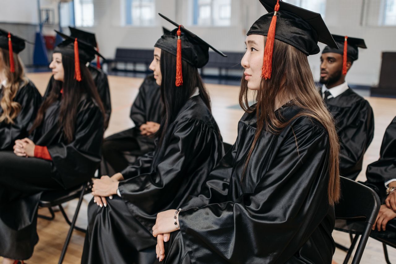 The Art of Drawing Readers In: Your attractive post title goes here Graduates in caps and gowns seated indoors during a ceremony, celebrating academic success together.